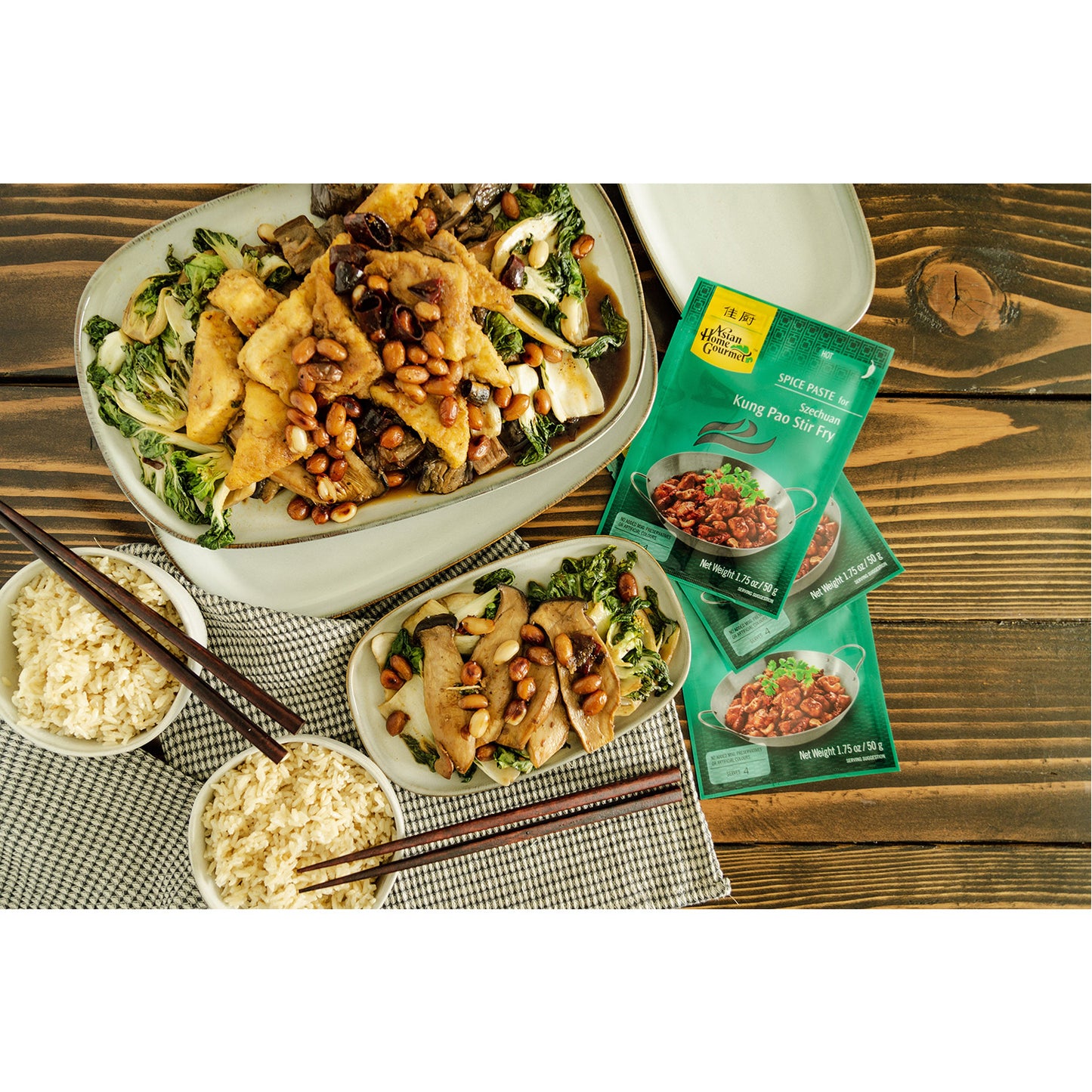 lifestyle photograph of kung pao stir fry vegetarian style served with tofu and peanuts. 2 bowls of rice and chopsticks pictured.