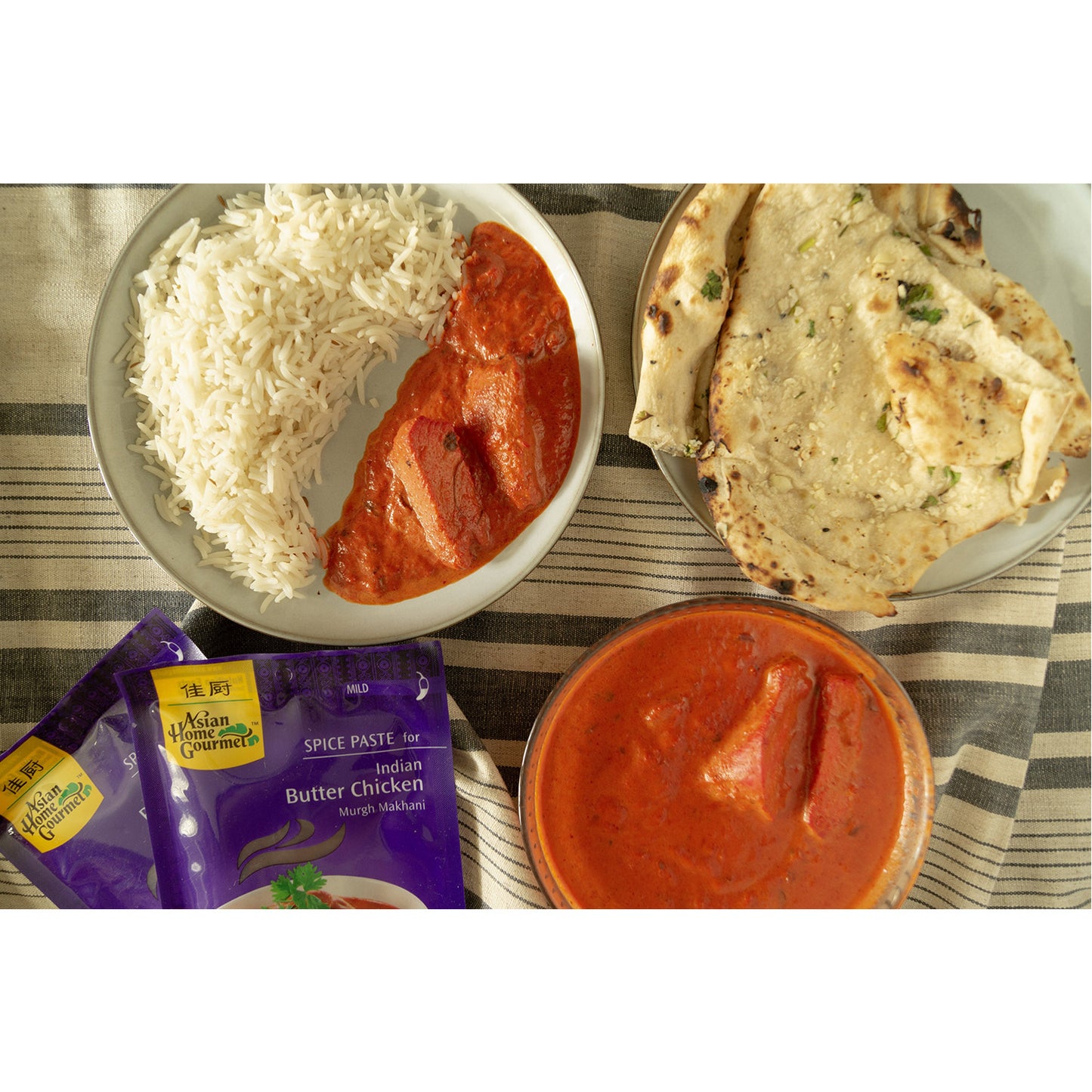 Lifestyle photograph of butter chicken curry with a side of rice and naan.