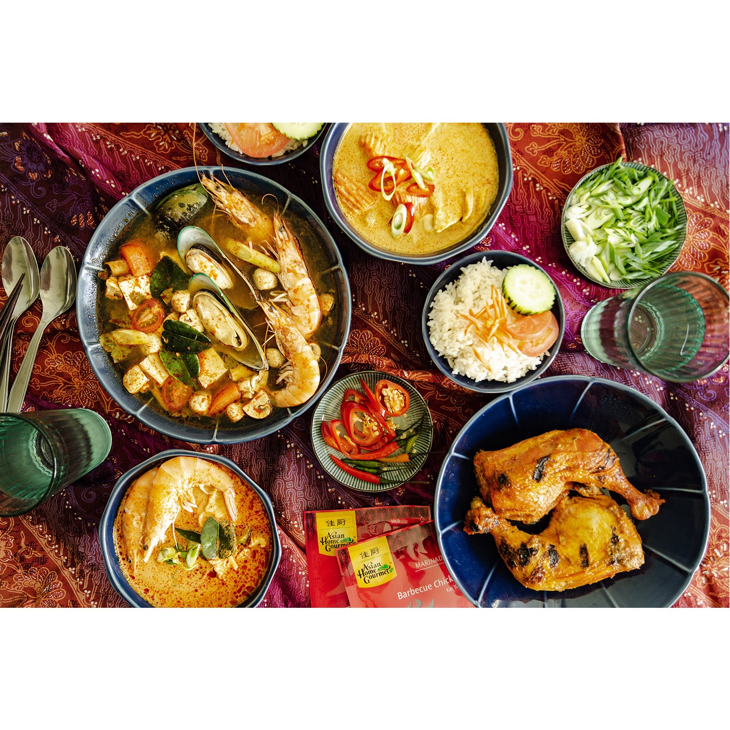 Lifestyle photograph of traditional Thai cuisines, Seafood Tom Yum soup, yellow curry, grilled chicken served with fresh chilis and vegetables.