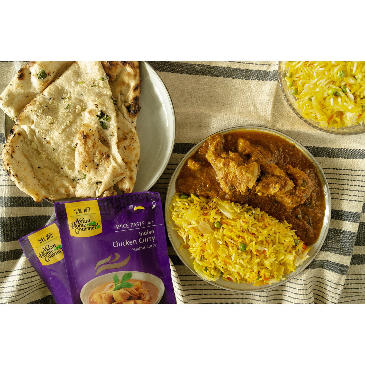 lifestyle photograph of traditional Indian cuisine, chicken curry with a side of yellow rice and garlic naan.
