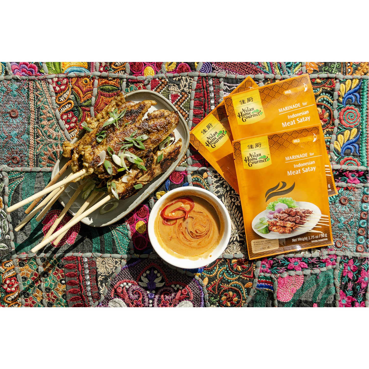 Lifestyle photograph of chicken skewer and peanut sauce laid on a traditional picnic blanket.