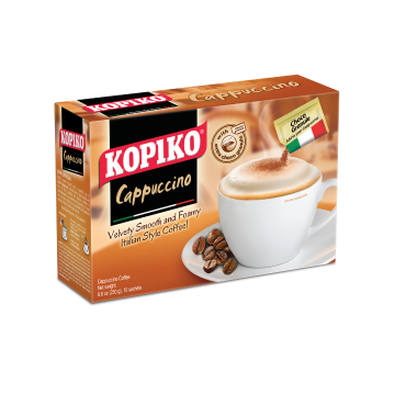 A brown Kopiko Cappuccino box with coffee mug and saucer set. A foamy cappuccino coffee in the cup with a chocolate granule sachet being sprinkled into the cup. Coffee beans in the saucer is pictured. Velvety smooth and foamy Italian style coffee.